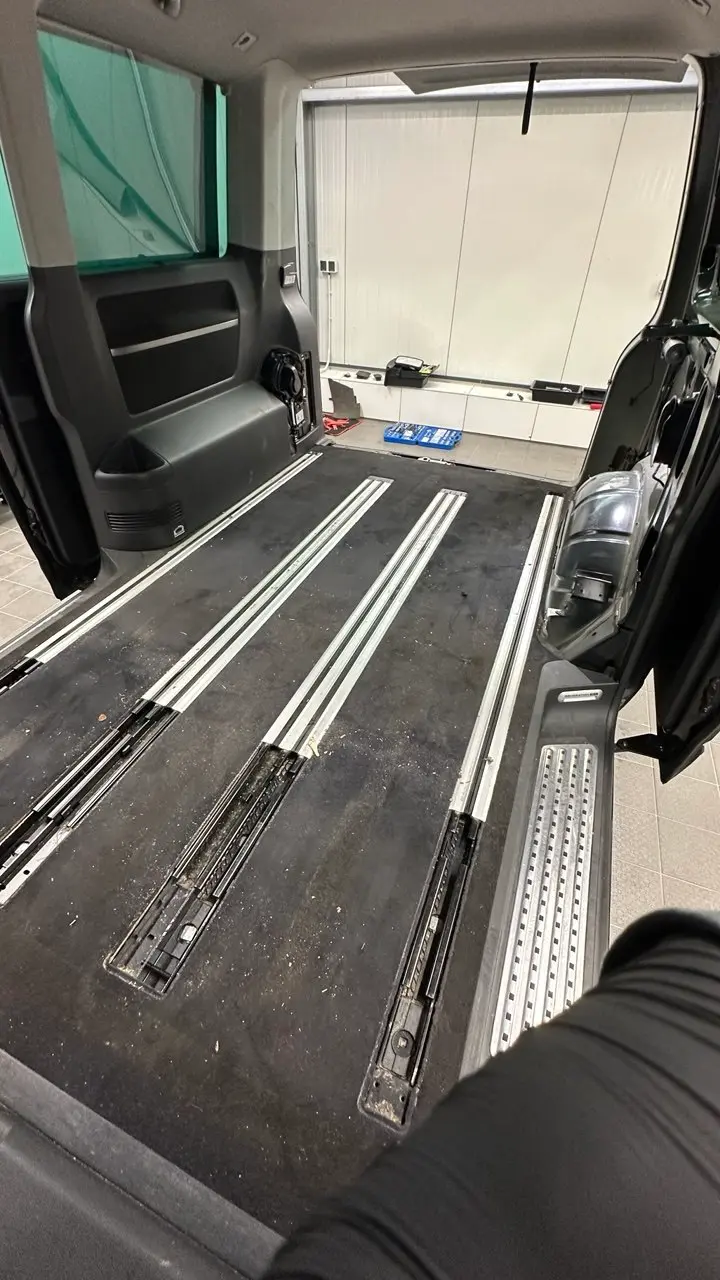 VW T6 Multivan mit ausgebauten Sitzen — Laderaum und Sitzschienen vor der Innenraumreinigung